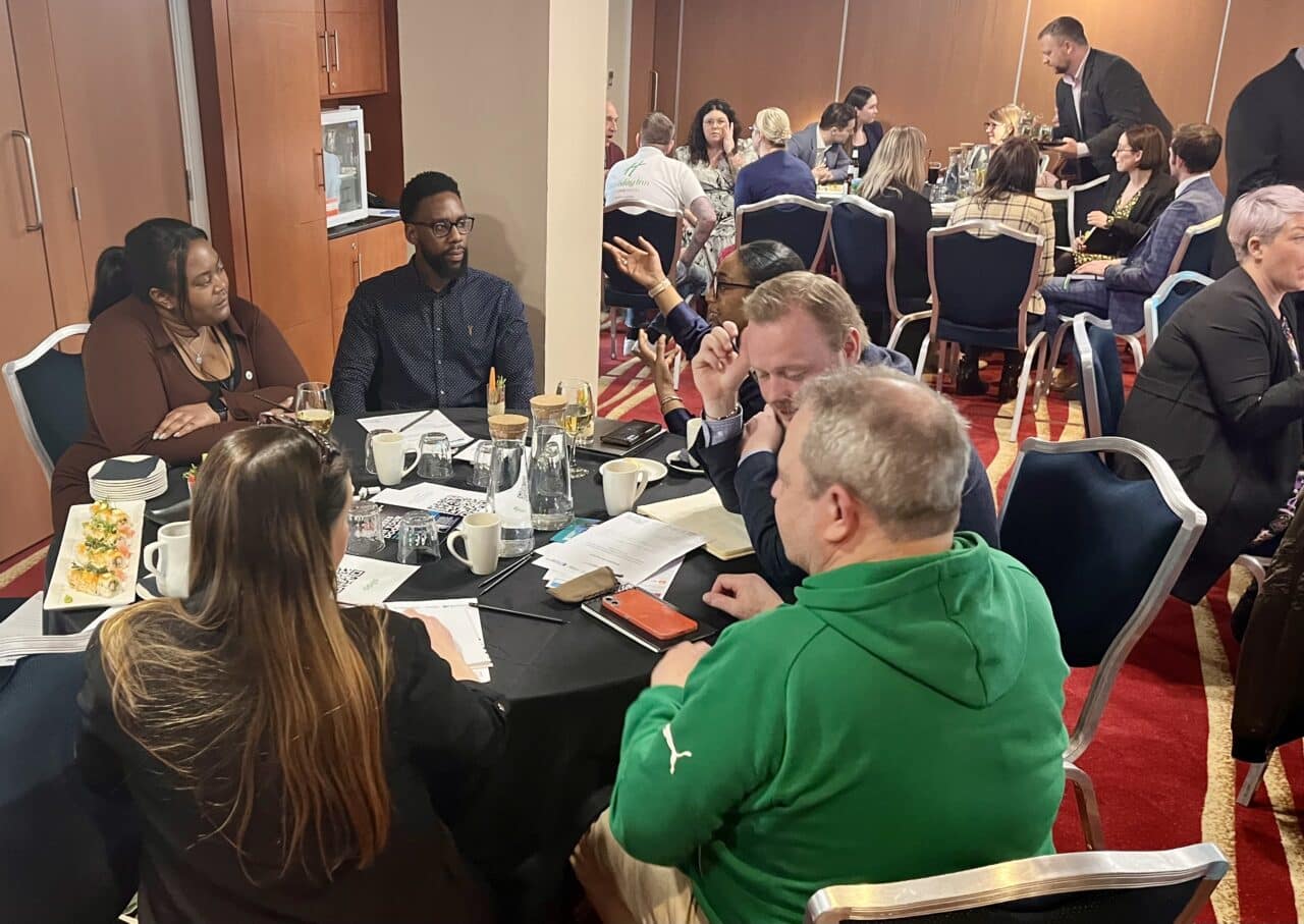 Hospitality Connect event - a group of people around a table at the event.