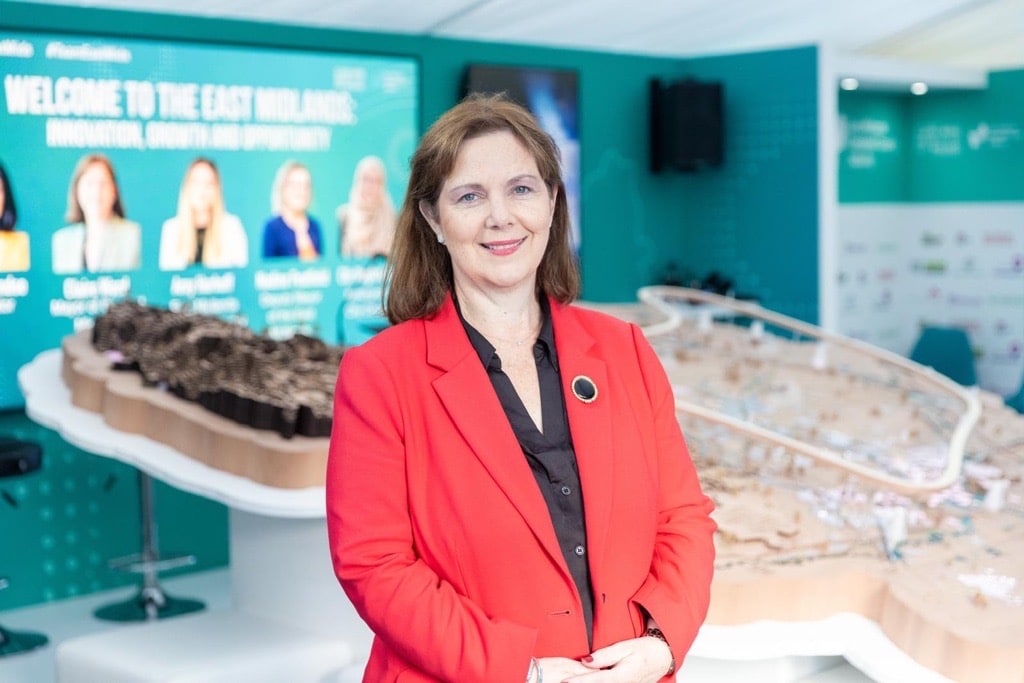 Mayor Claire Ward stand in front of a map of the region at UKREiiF