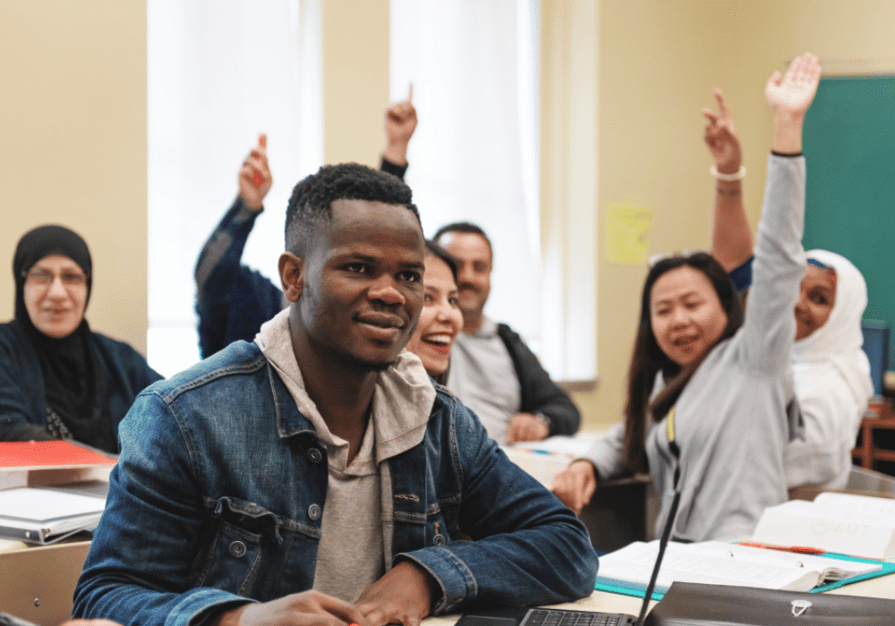 Diverse students in classroom with hands raised