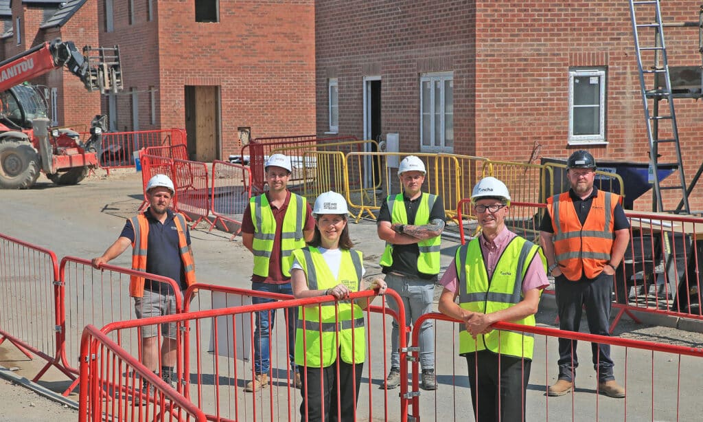 A group of people, including Mayor Claire Ward, are standing on a construction site. They are wearing high-vis vests and hard hats.