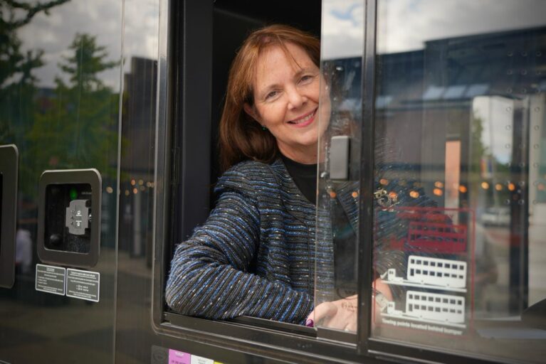 Mayor Claire leans out of the driver's window of a bus.