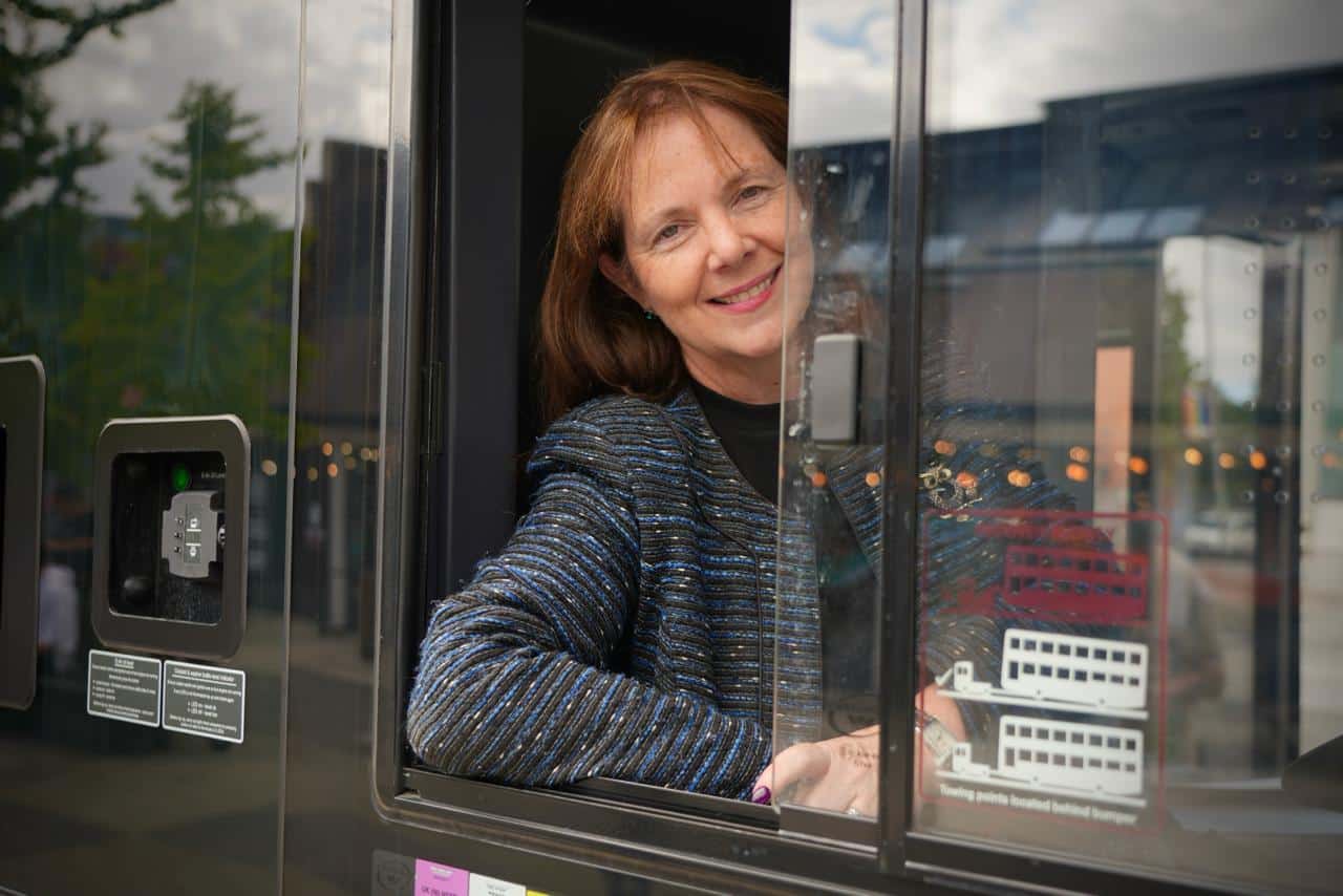 Mayor Claire leans out of the driver's window of a bus.