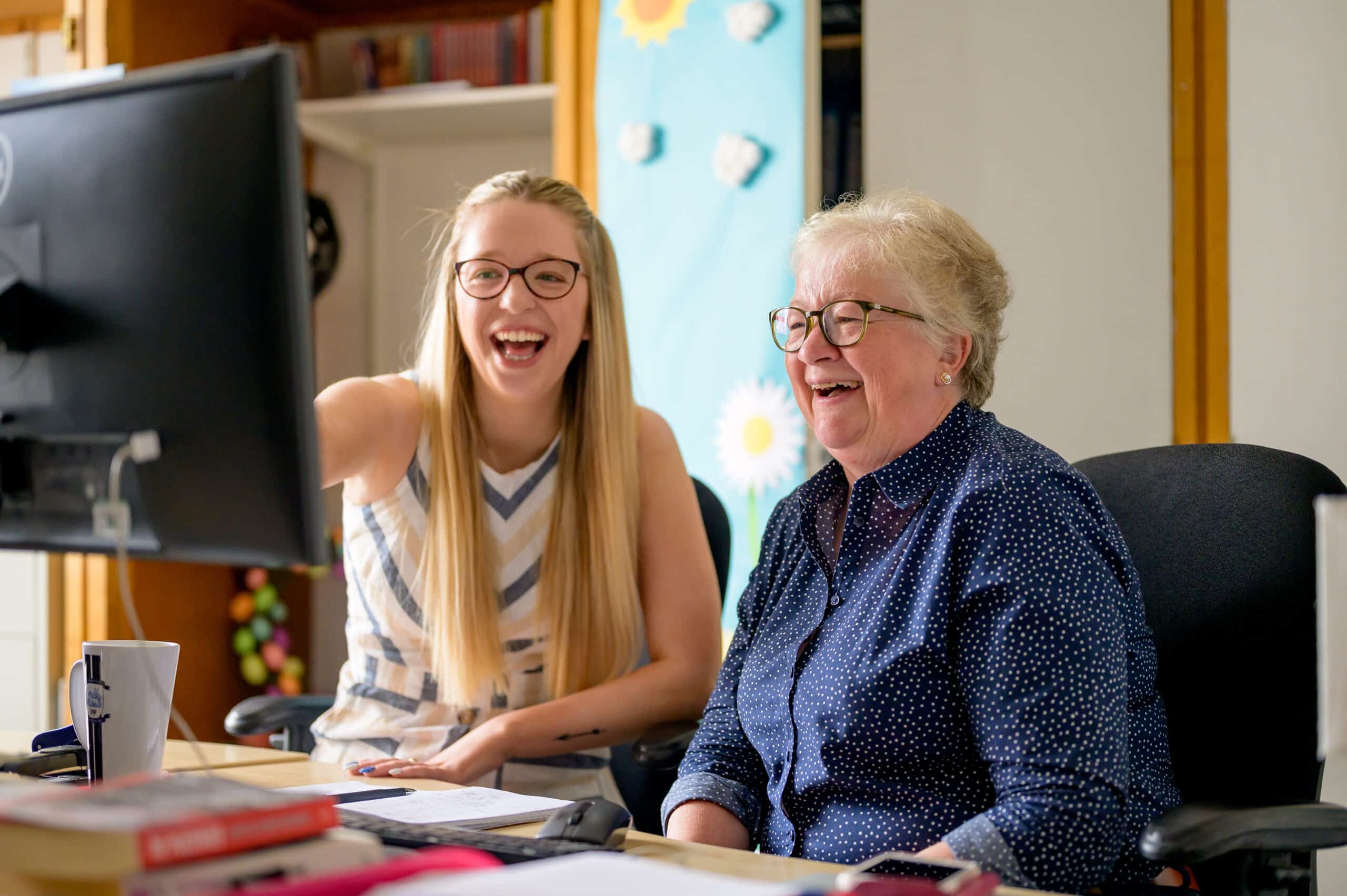 Two women smile at a computer screen